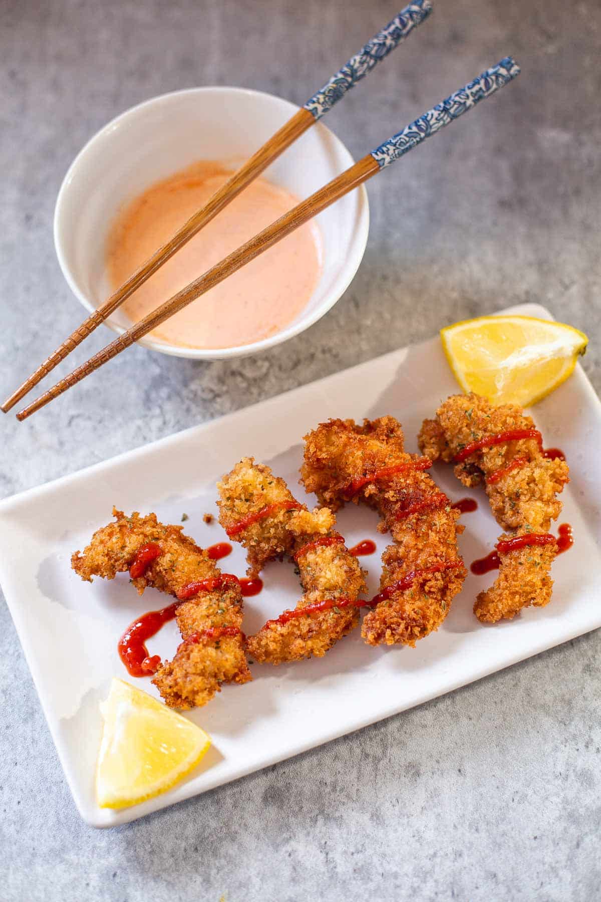 panko shrimp with sriracha and lemon wedges beside spicy mayo and chopsticks