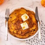 pumpkin spiced pancakes on plate with butter, fork, knife, and napkin with bats on it