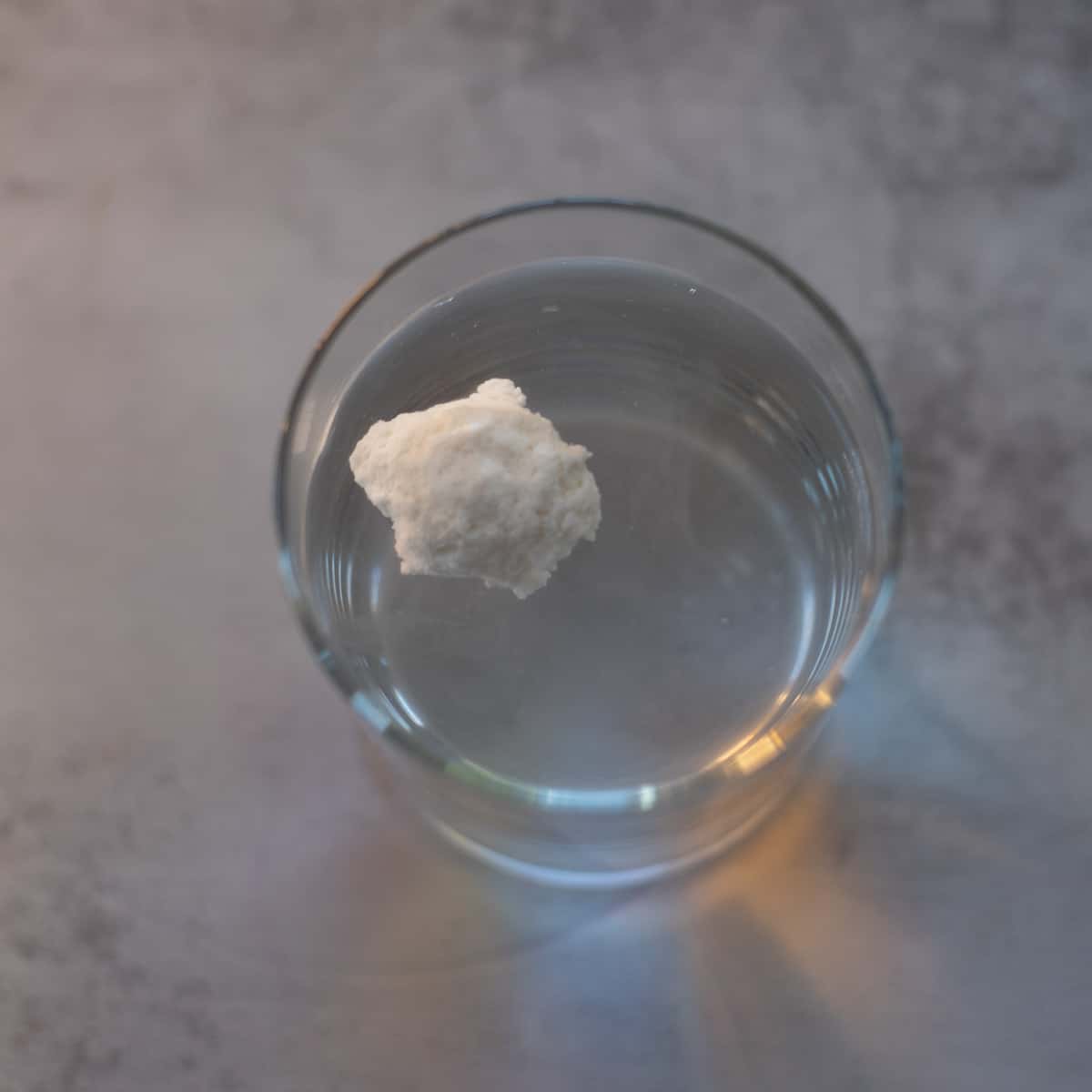a blob of sourdough starter floating in a glass of water