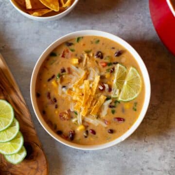 mexican bean soup in bowl with lime wedges, knife, and bowl of tortilla chips