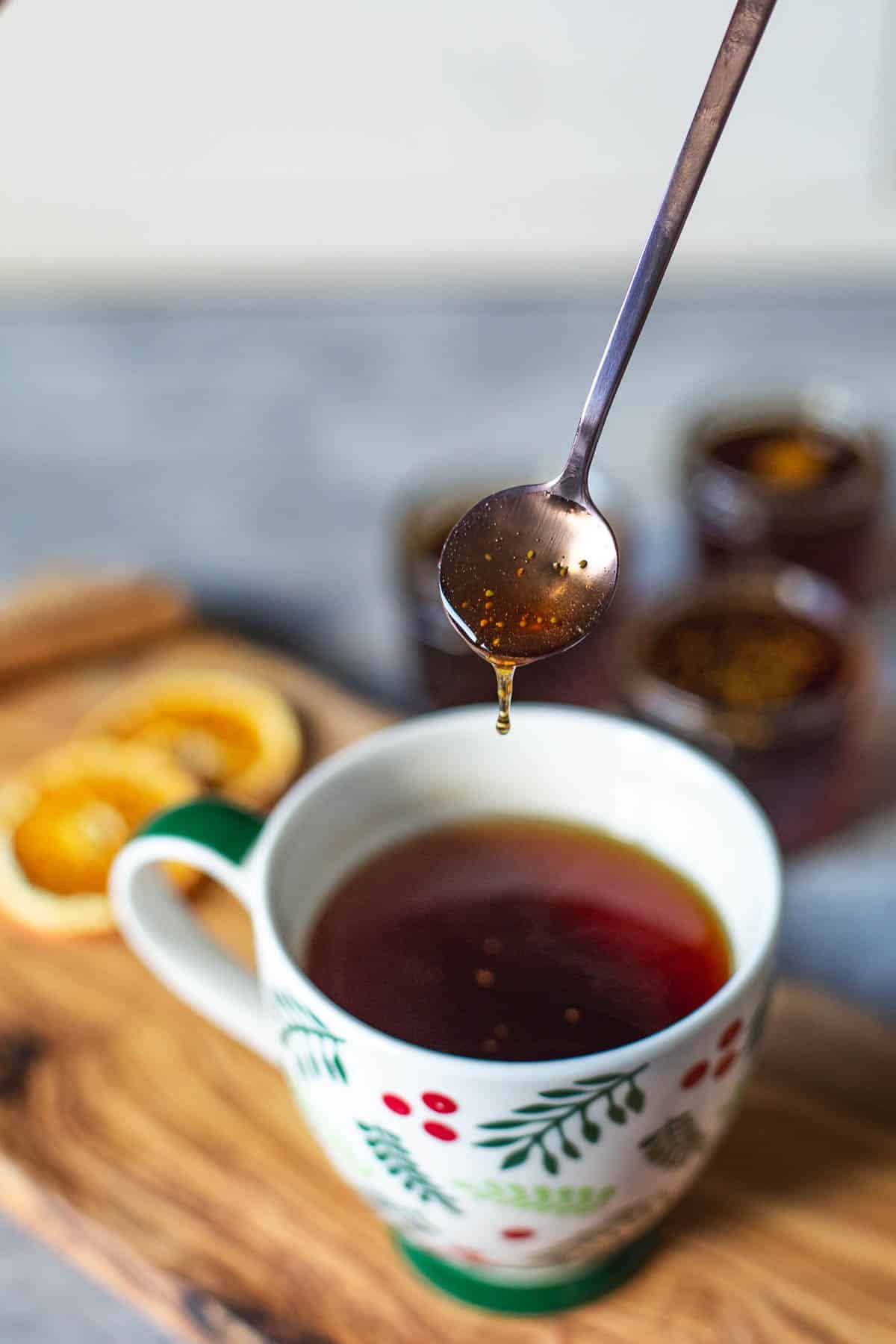 fig syrup being drizzlef with small spoon into cup of tea