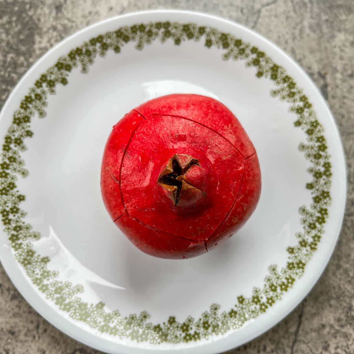 a scored pomegranate on a white plate