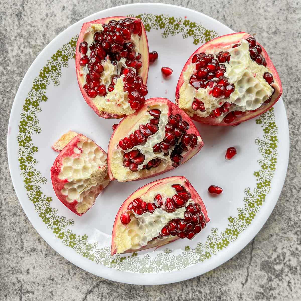 a pomegranate split into sections on a white plate