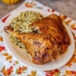 baked turkey legs and wild rice on white plate over a fall themed napkin