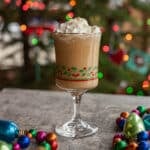 Christmas whiskey cocktail with Christmas tree in the background