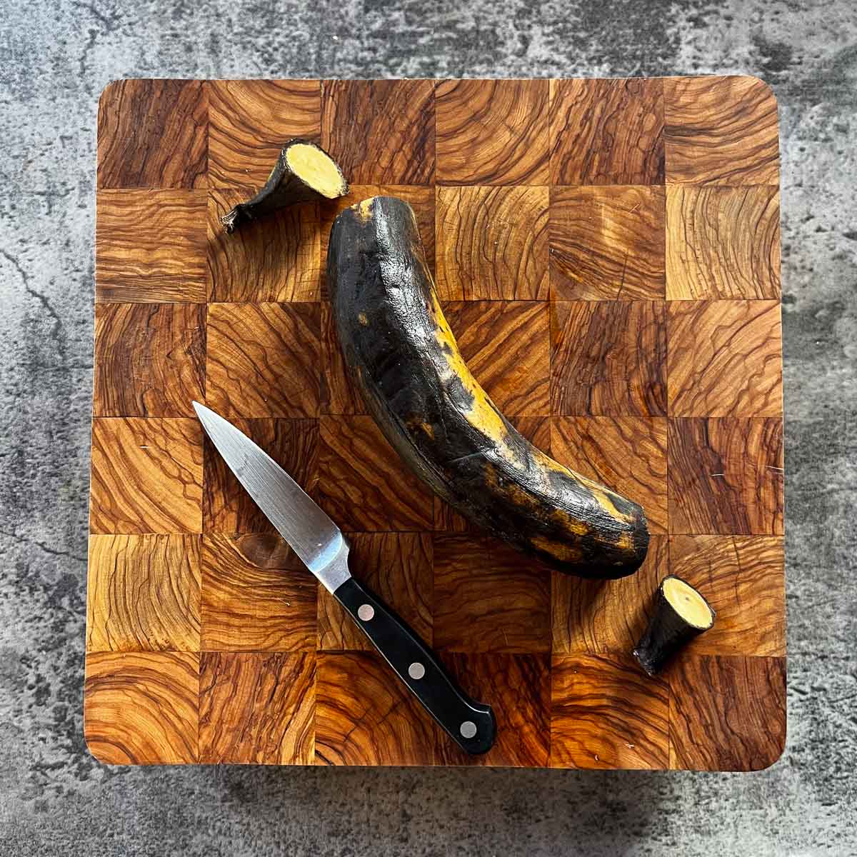 plantain with ends cut off on cutting board beside knife