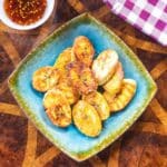 air fryer plantains on square plate beside bibimbap sauce bowl and kitchen towel
