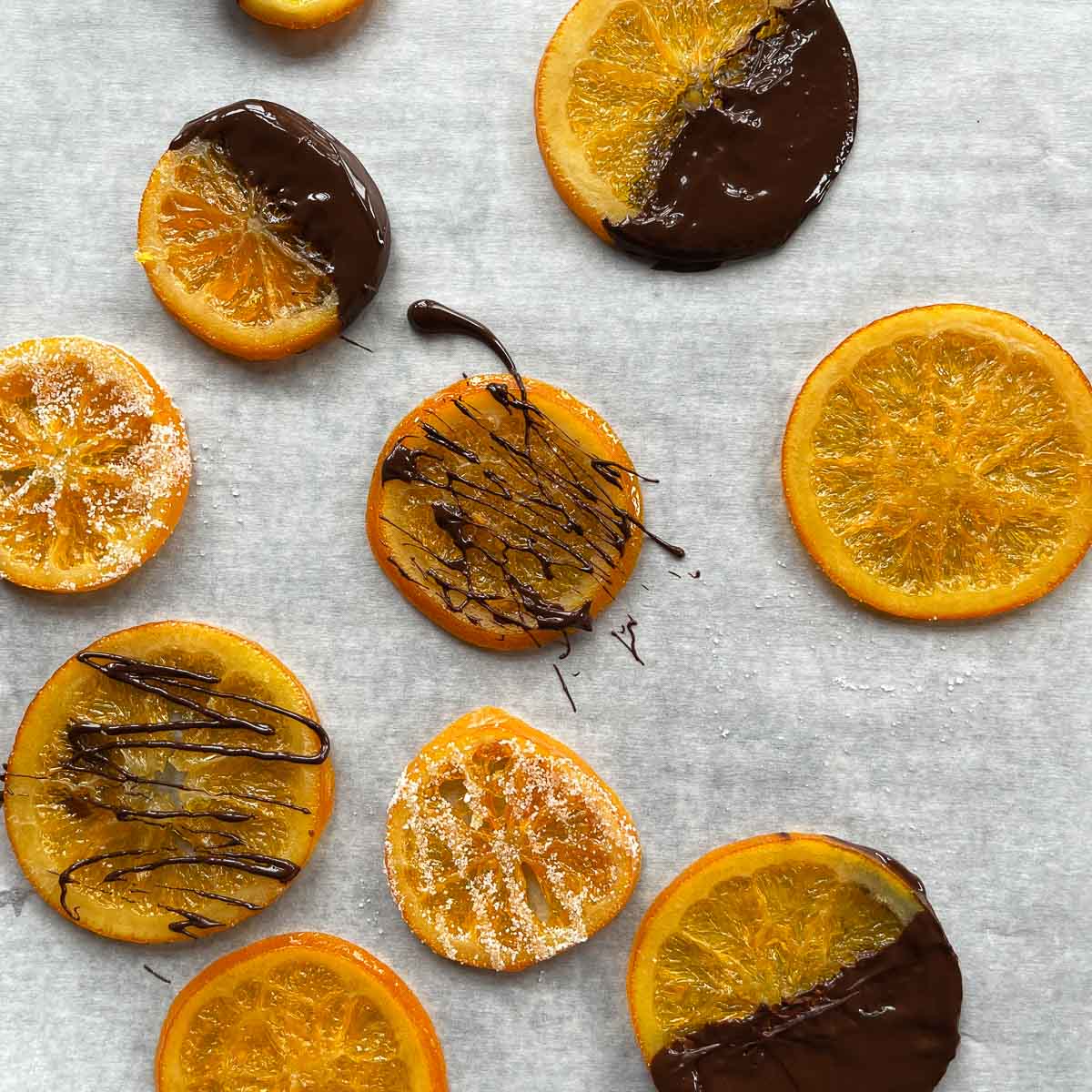 candied orange slices dipped in chocolate on parchment paper