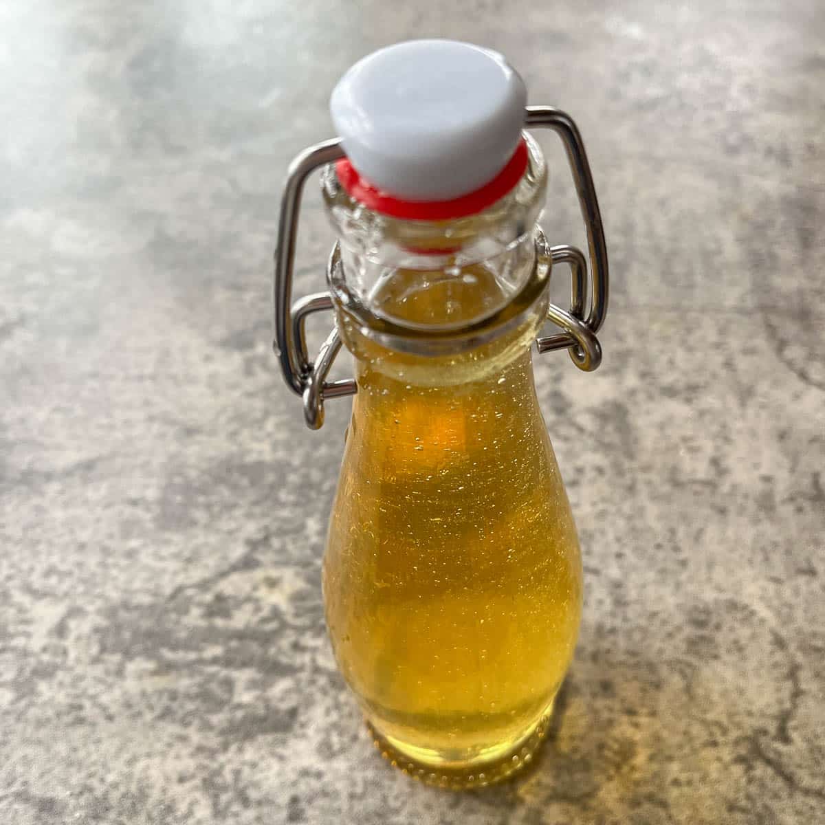a bottle of orange syrup in a flip top bottle