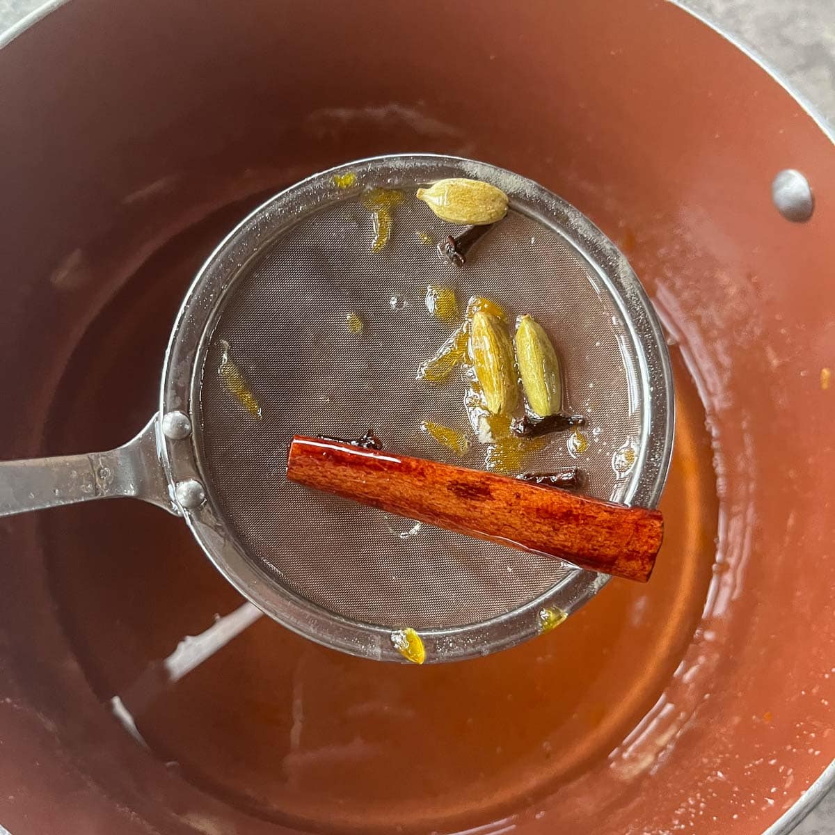 removing spices from a pot of syrup
