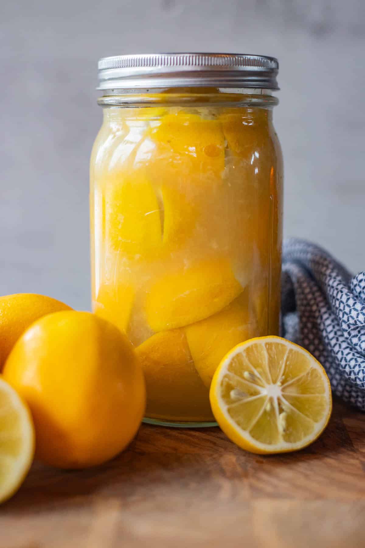 moroccan preserved lemons in a jar with more lemons around it
