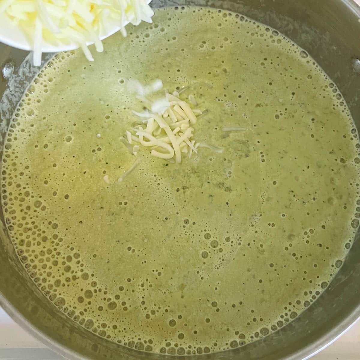 cheese being added to blended cream of jalapeno soup
