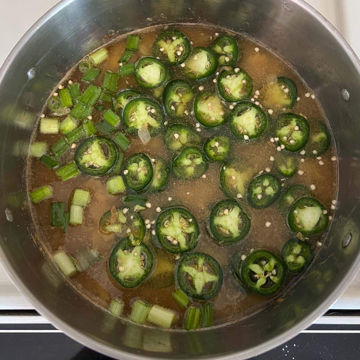 broth, jalapeños, and green onion added to pot