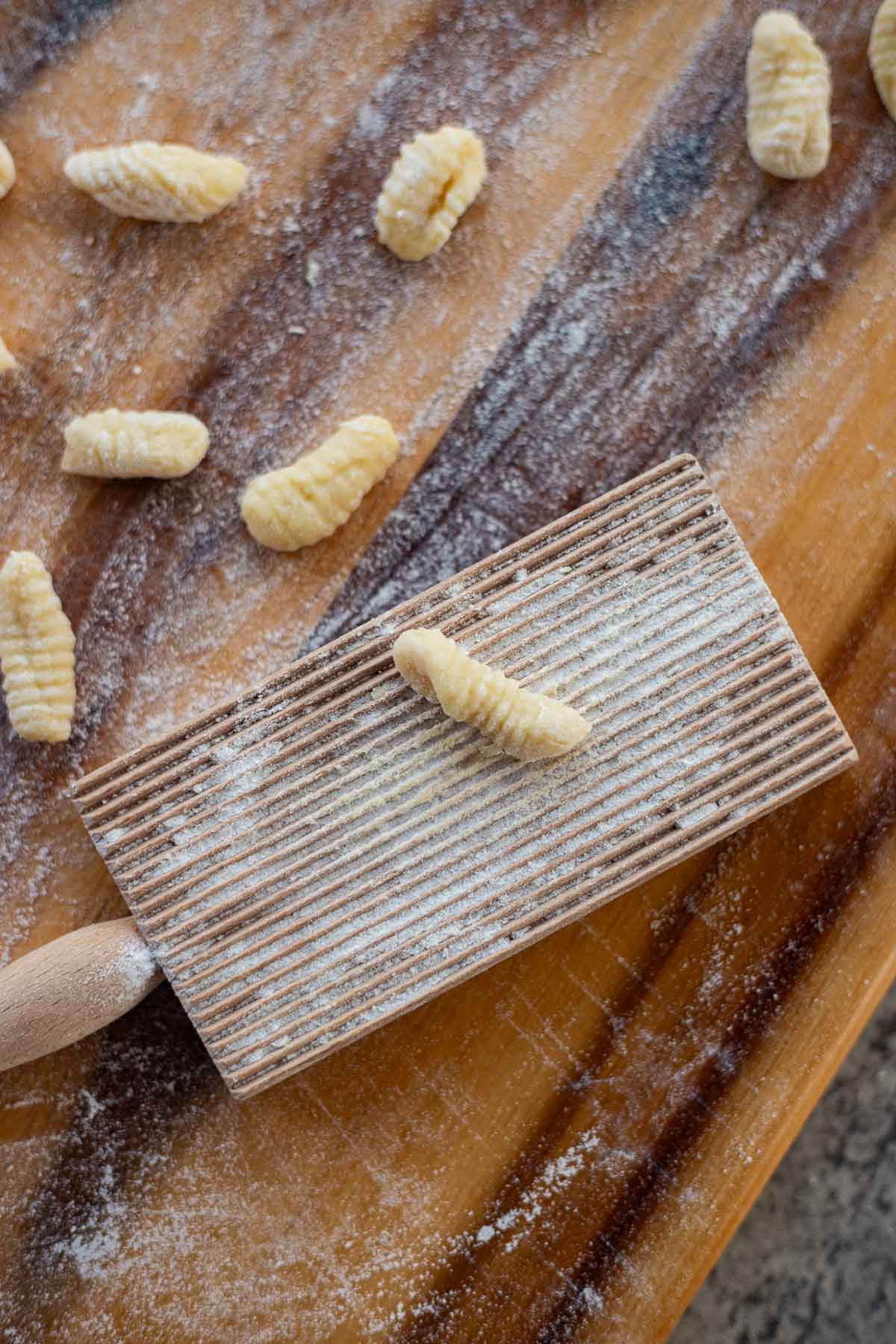 potato pasta on a gnocchi board with more pasta around it