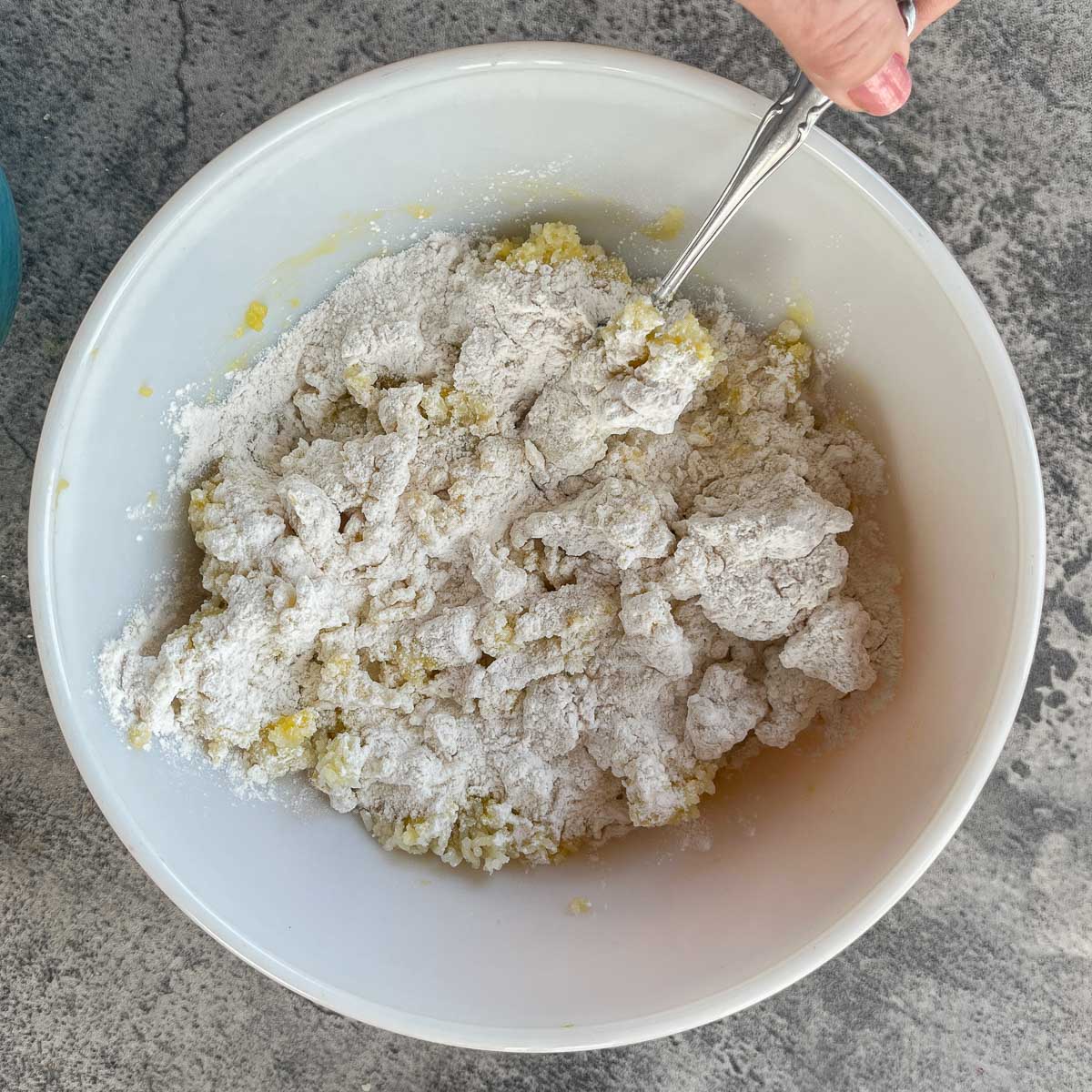 stirring potato pasta ingredients in a white bowl.