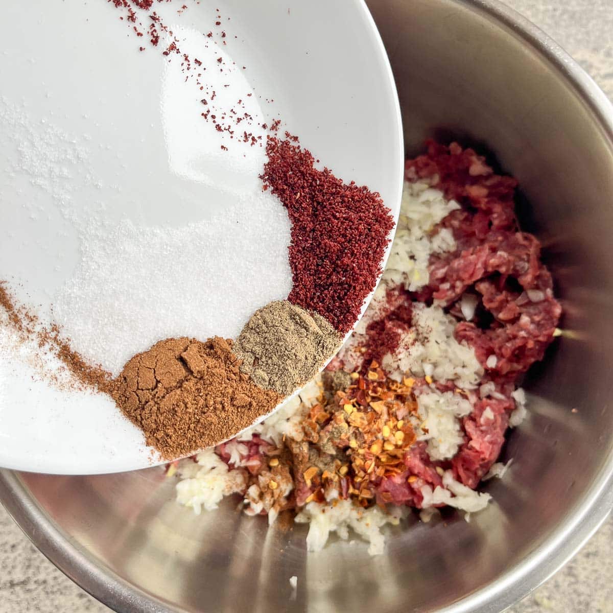 adding spices to ground meat in a bowl