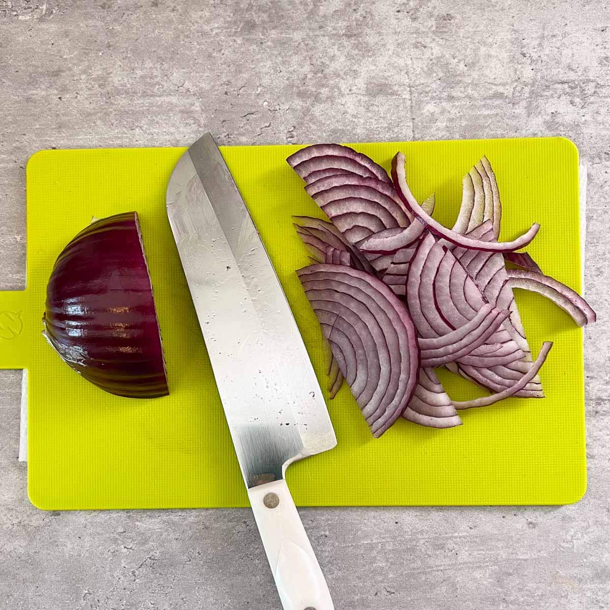 red onions being chopped on cutting board with knife