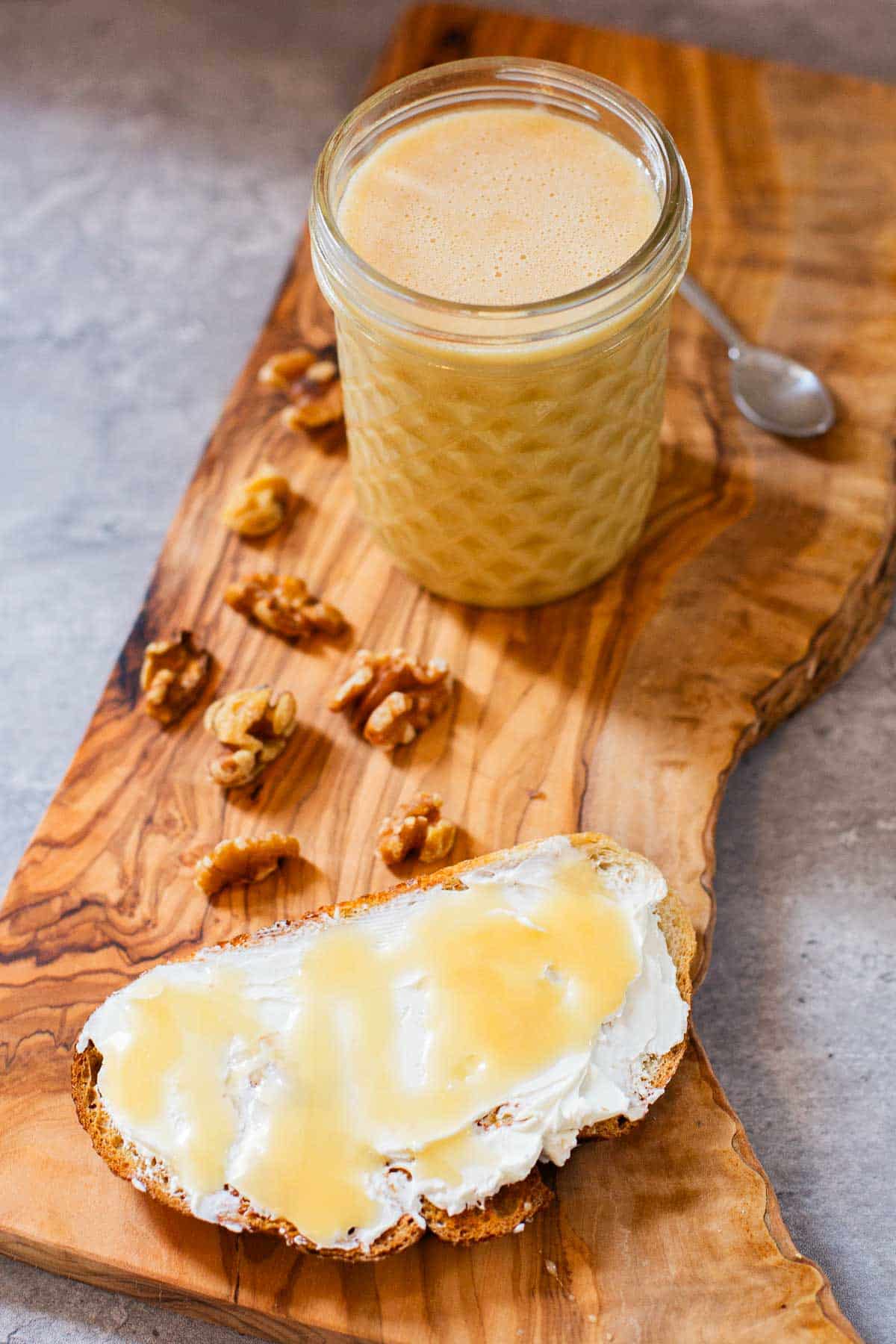 whipped honey (creamed honey) in mason jar on cutting board with walnuts and sourdough toast with cream cheese and whipped honey