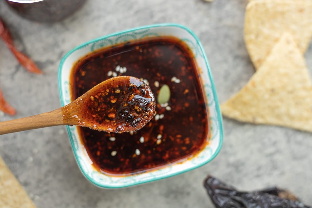 a bowl of macha salsa with a spoon in it and chips next to it