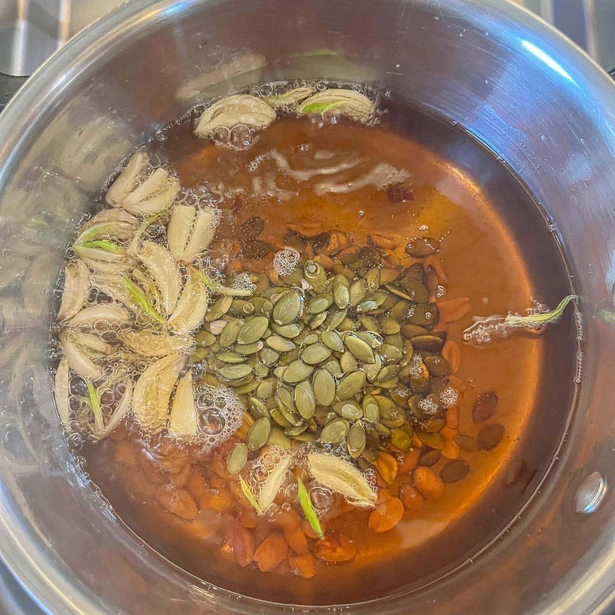 garlic, peanuts, and pumpkin seeds frying in a pot of oil