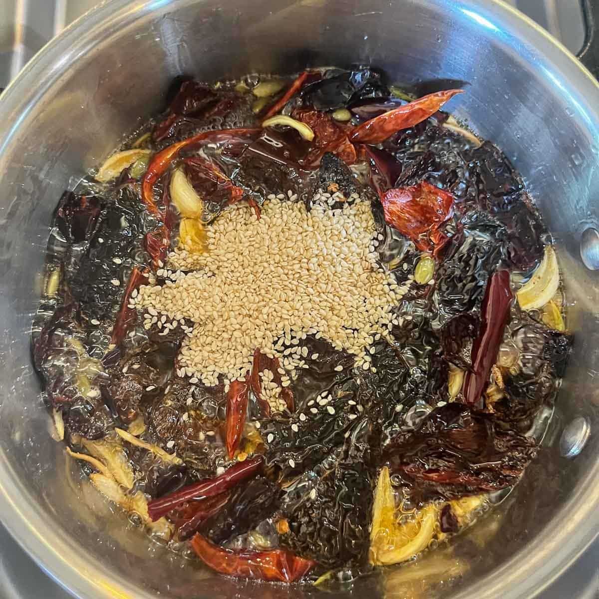 chiles and sesame seeds in a pot of oil