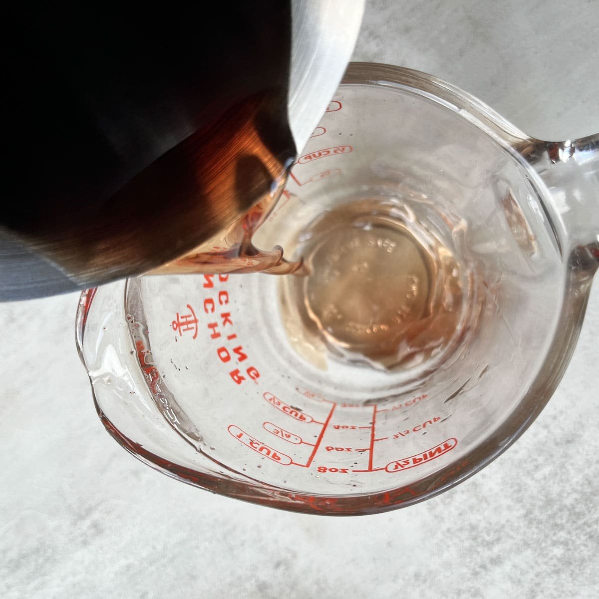 pouring balm of gilead oil into a measuring cup.