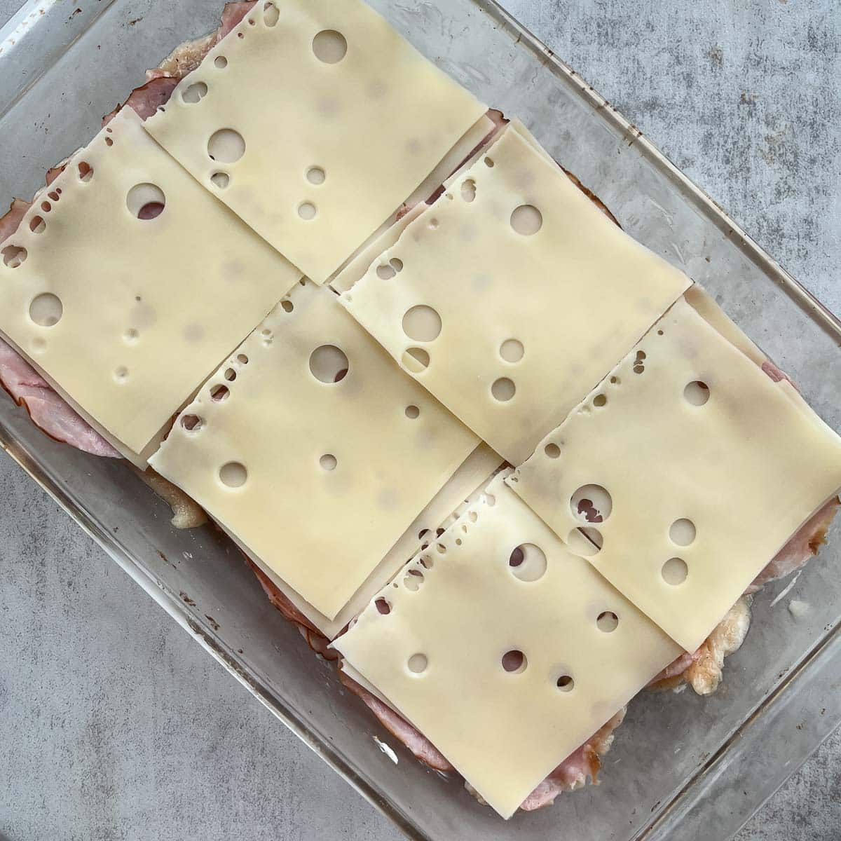 slayers of chicken and Swiss cheese in a baking dish.