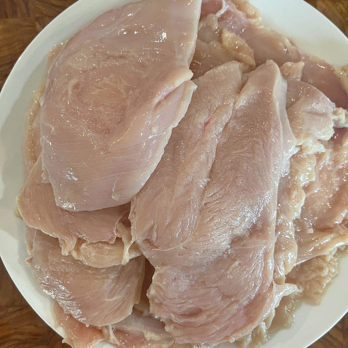 chicken breasts raw, in a white bowl.