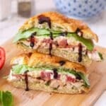 chicken croissant sandwich cut in half with balsamic glaze drizzled over it