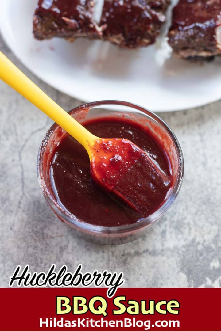 huckleberry bbq sauce in a jar with a yellow brush over it and ribs in the background