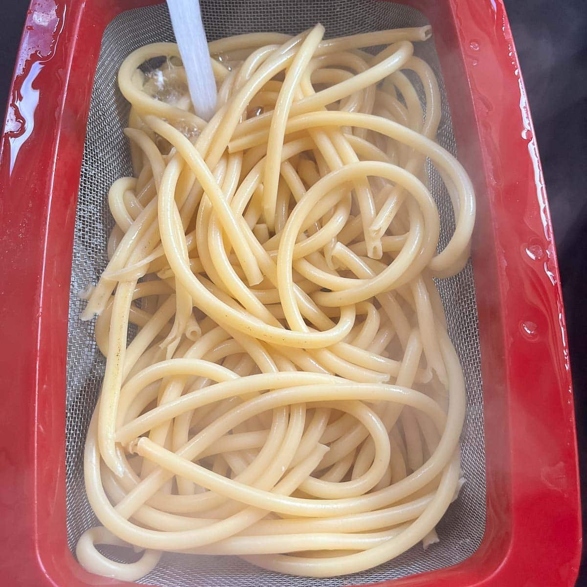 pasta noodles being rinsed with water.