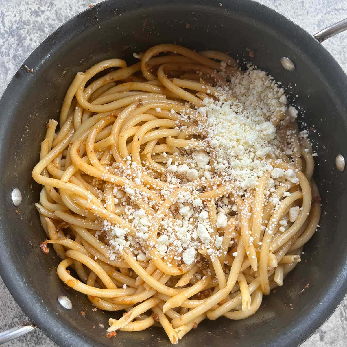 a pot of pastitsio noodles with cheese sprinkled on them.