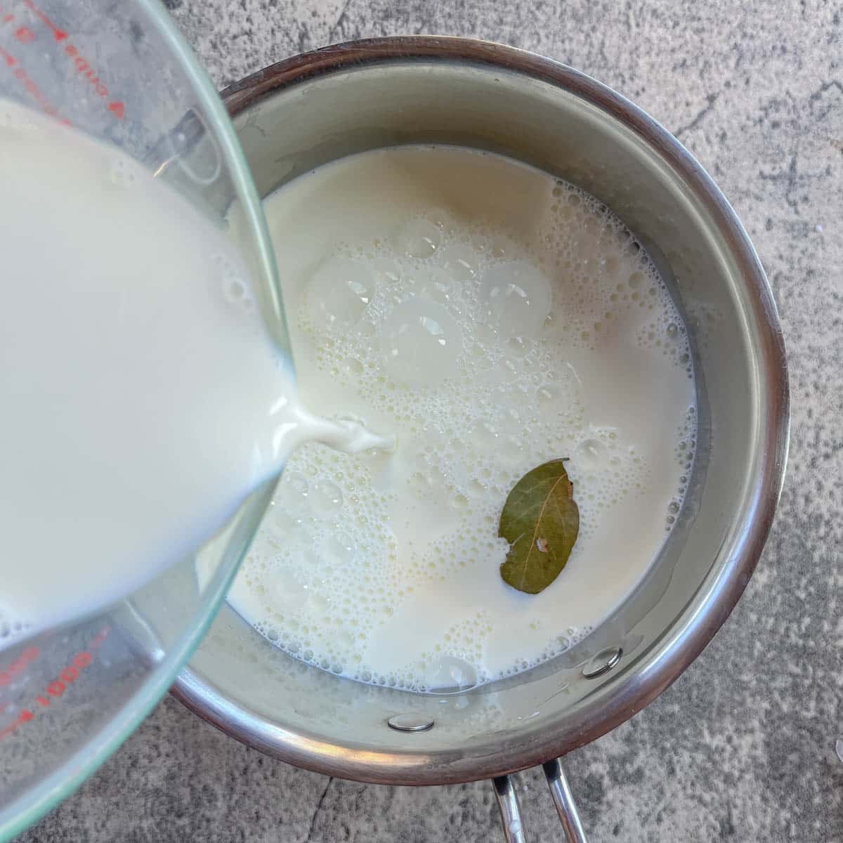 adding milk to a small pot.