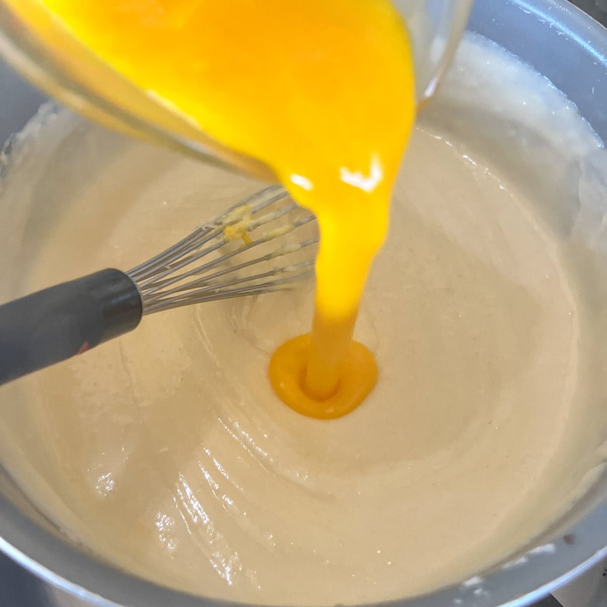pouring eggs into béchamel sauce.
