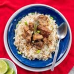 pork adobo over rice on a blue plate with a red napkin under it