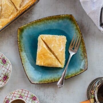 Galaktoboureko on a blue plate with coffee next to it