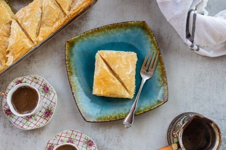 Greek Galaktoboureko on a blue plate with turkish coffee