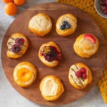 crescent roll cream cheese danishes with various toppings on cutting board beside fruits