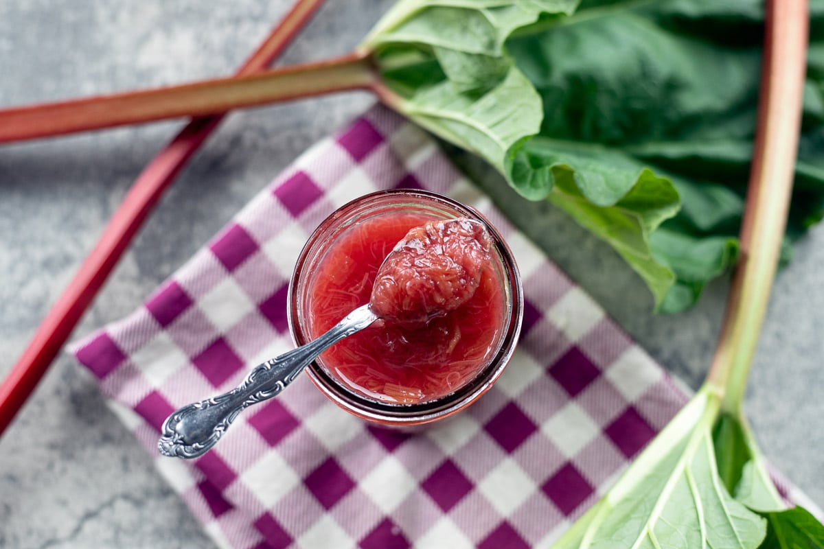 rhubarb sauce in a jar with more rhubarb around it