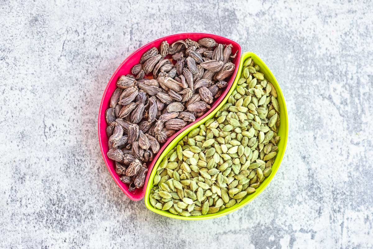 black and green cardamom pods in two different bowls