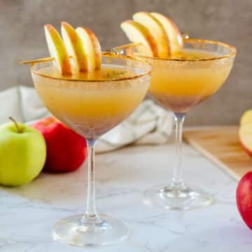 two apple cider martinis beside fresh apples and washcloth