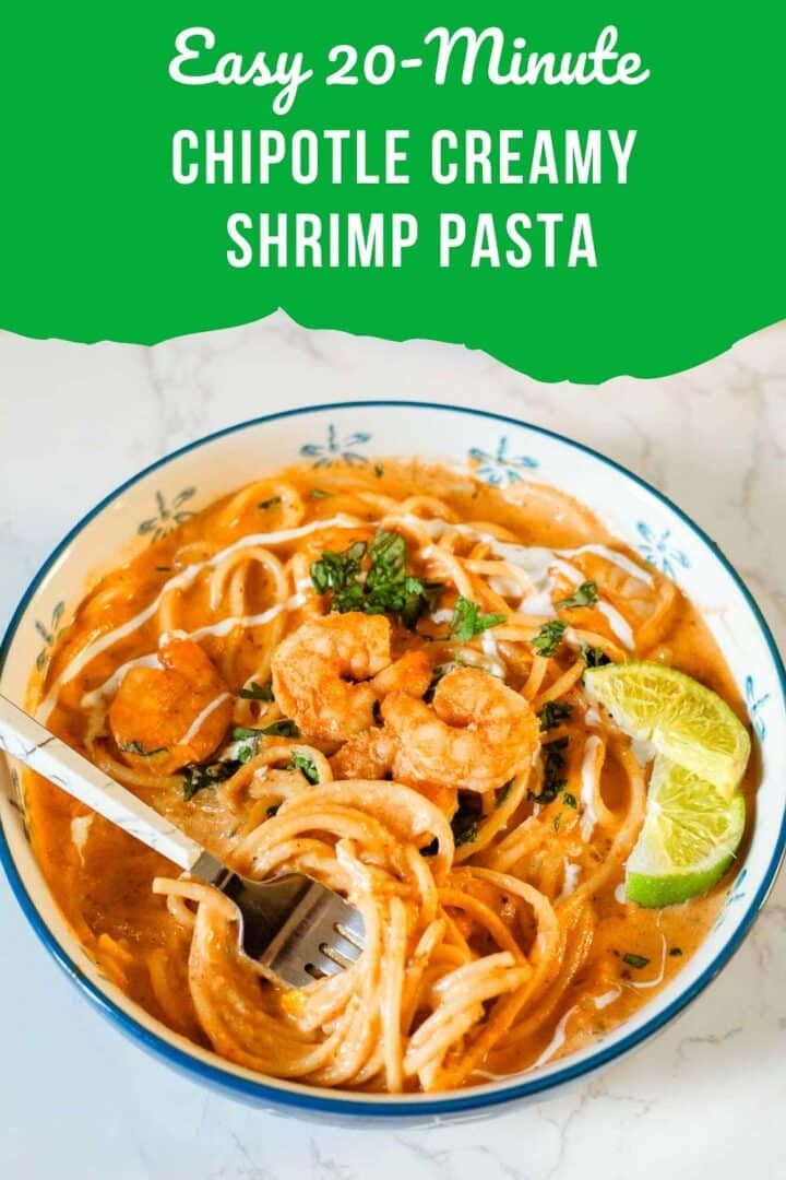 creamy shrimp pasta in bowl with fork and lime slices beside veggies