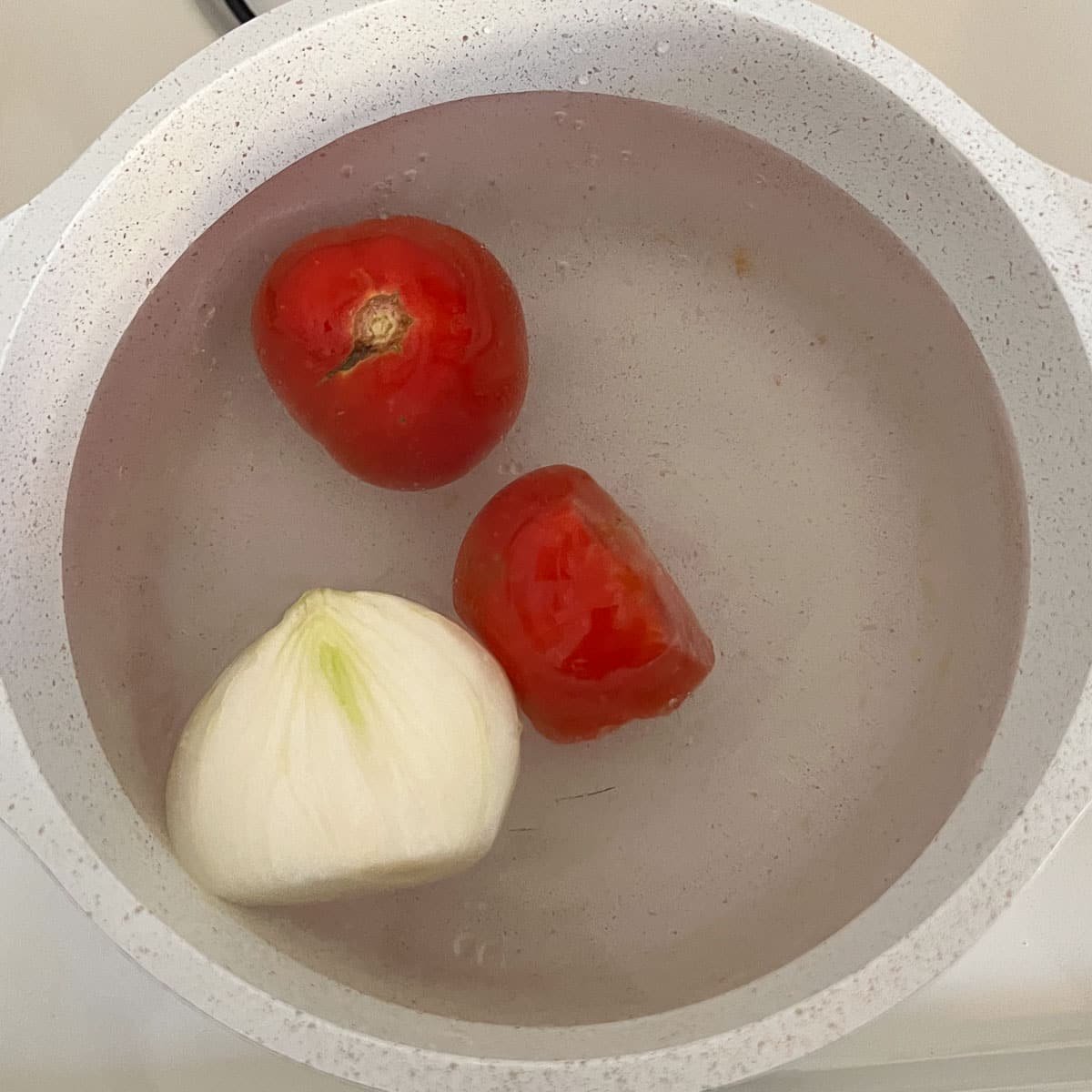 tomatoes and onion in pot of water