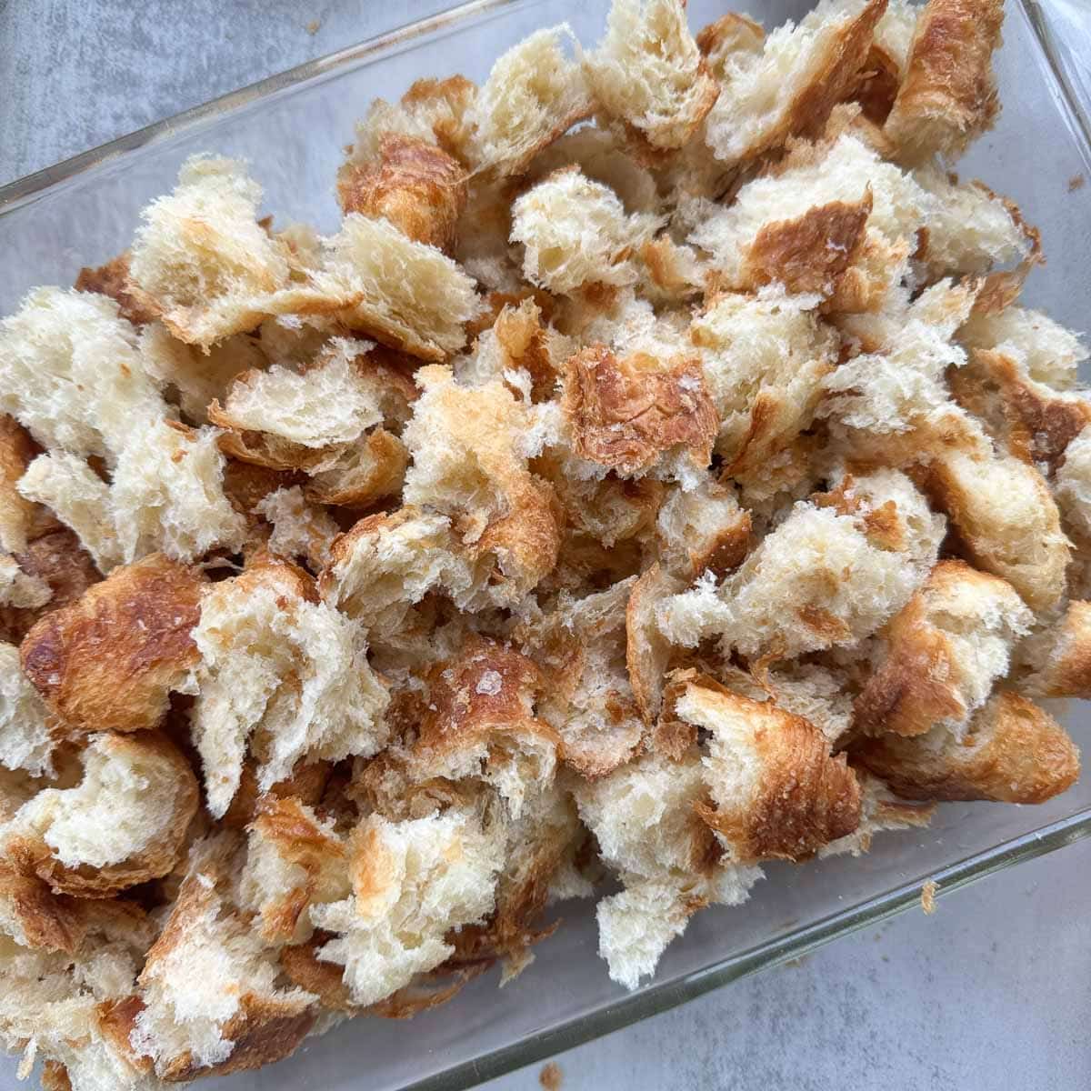 chunks of croissant bread in a baking pan