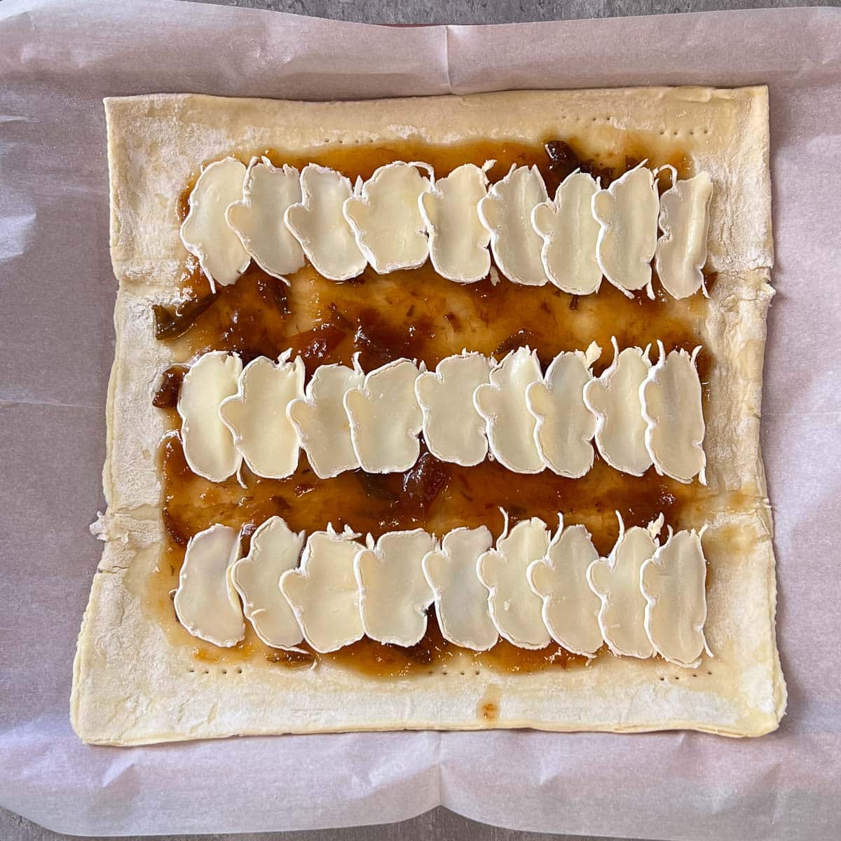 rows of sliced brie on puff pastry tart