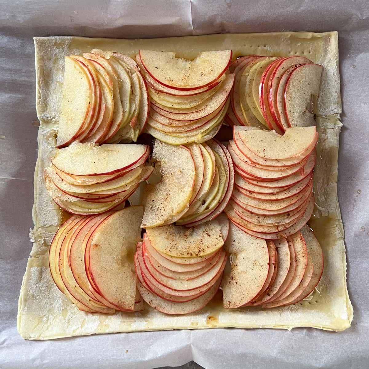 apple slices arranged on puff pastry tart before cooking