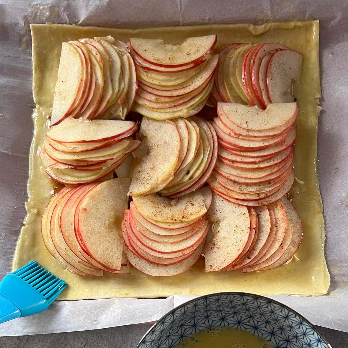 brushing egg wash on the edges of apple tart