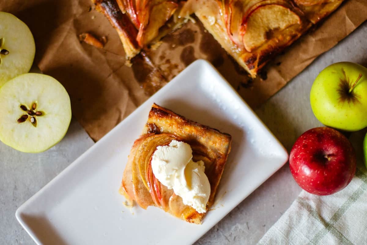 slice of apple tart with ice cream on top and apples on the side