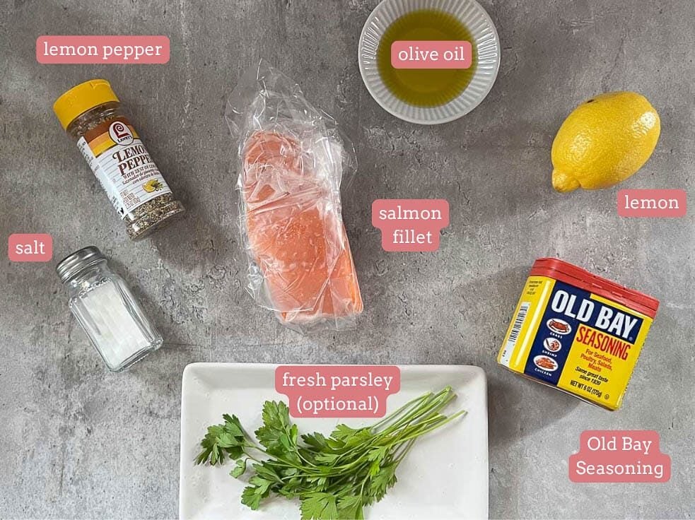 salmon, fresh parsley, lemon, and spices on a gray surface.
