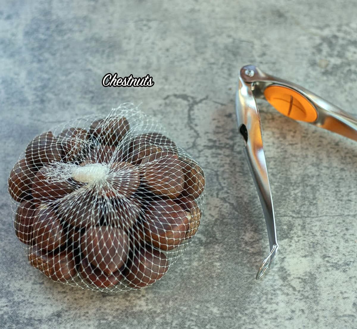 chestnuts in a mesh bad with a chestnut tool next to it.